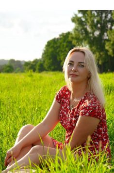 Polnische Single Frauen suchen nach Liebe und einem Partner fürs Leben. Hier siehst du eine wunderschöne Frau, die auf einer grünen Wiese sitzt und in die Ferne blickt.