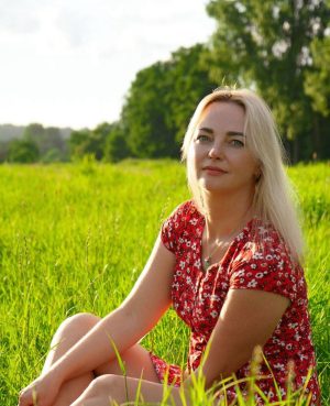 Polnische Single Frauen suchen nach Liebe und einem Partner fürs Leben. Hier siehst du eine wunderschöne Frau, die auf einer grünen Wiese sitzt und in die Ferne blickt.