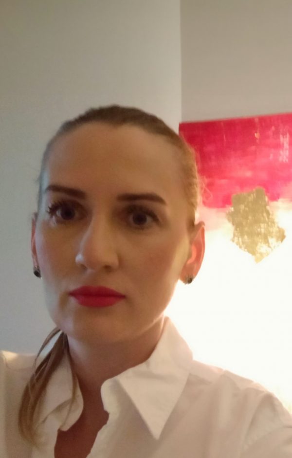 Nahaufnahme von Liubov, 38 Jahre alt, mit roten Lippen und weißem Hemd, vor einem Kunstwerk. Ukrainische Single Frauen, die eine ernsthafte Beziehung suchen.