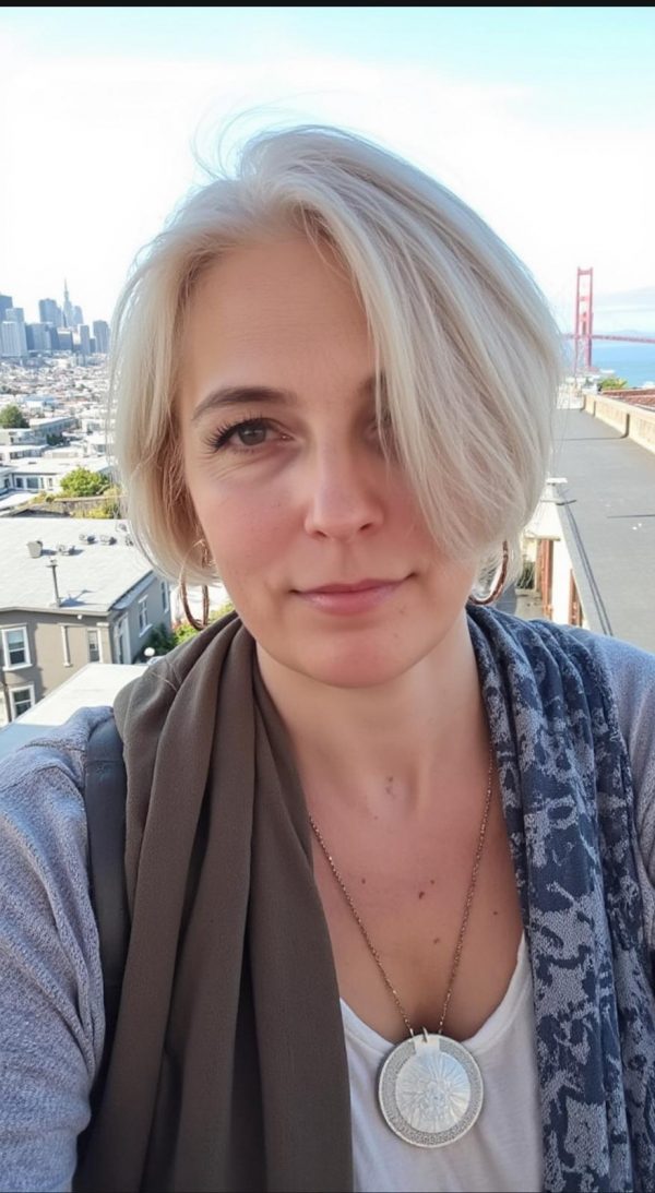 Irina, 55, posiert für ein Foto mit einer urbanen Landschaft im Hintergrund. Sie trägt einen Schal und eine Halskette; im Hintergrund sind Häuser und der Golden Gate Bridge in San Francisco zu sehen. Ausländische Single Frauen und Damen aus Osteuropa suchen eine Heiratsvermittlung in Deutschland.