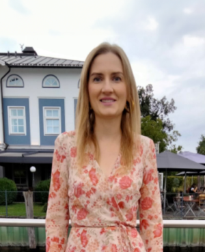 Profilbild von Liubov, 38 Jahre alt, in einem geblümten Kleid vor einem Gewässer und einem stilvollen Gebäude. Ukrainische Single Frauen, die eine ernsthafte Beziehung suchen.